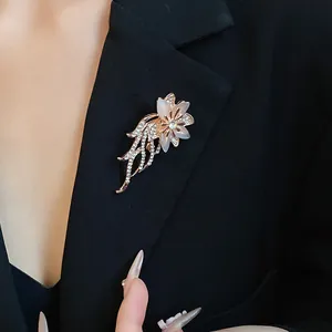 Primo piano di un'elegante spilla a fiore con pietra occhio di gatto e cristalli su blazer