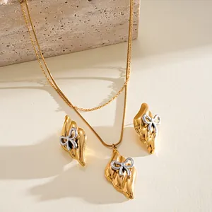 Macro view of vintage style gold and silver toned stainless steel bow necklace and earrings set
