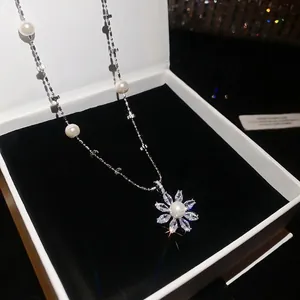 Elegant silver flower pendant necklace with pearls and sparkling zircons in a box