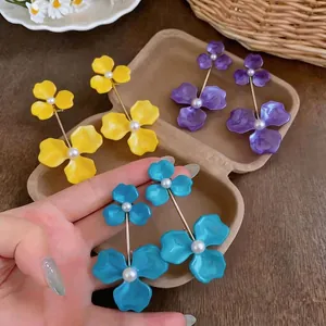 Stylish enamel flower drop earrings with pearl accents in vibrant yellow, blue, and purple.