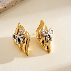 Detailed macro view of vintage gold stainless steel earrings with silver bow accents