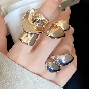 Close-up of irregular twisted metal rings featuring a glossy water-drop design in gold and silver
