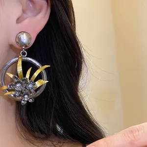 Close-up of vintage hollow circle earrings with gold leaf and floral rhinestone details.