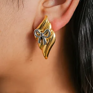 Close-up detail of vintage style gold and silver two-tone stainless steel bow earring