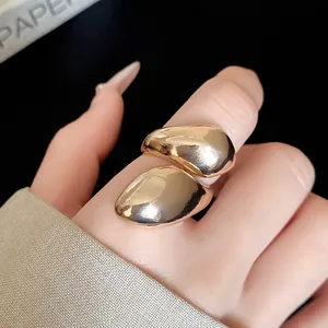 Detailed close-up showing a gold irregular distorted teardrop ring with a high-shine finish