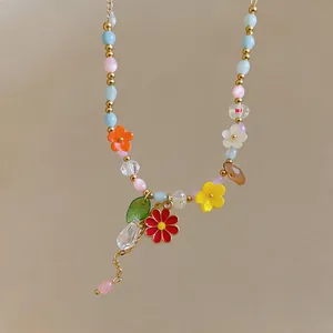 Primo piano di una collana di perline vivaci con fiori smaltati colorati e ciondoli.