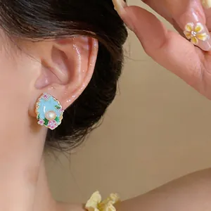 Dettaglio ravvicinato dell'orecchino ovale con perla, smalto azzurro e fiori rosa