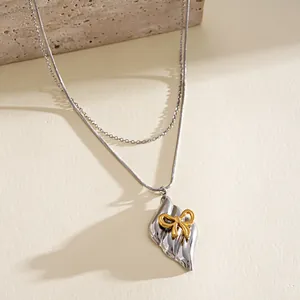 Elegant close-up detail of a stainless steel bow pendant necklace with gold and silver accents