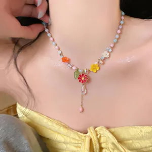 Primo piano di una collana di perle colorate con pendenti a fiore in smalto su modella