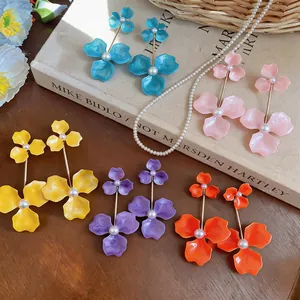 Detailed view of colorful enamel flower earrings with pearl centers on a vintage book