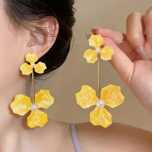 Close-up of vibrant yellow enamel flower drop earrings with elegant pearl centers