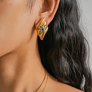 Detailed close-up view of a vintage gold earring with a silver bow accent on model's ear