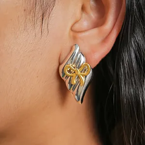 Detail shot of a two-tone silver and gold bow earring with vintage metallic texture