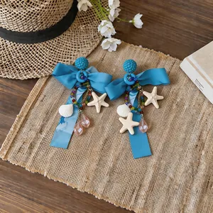 Dettaglio macro di eleganti orecchini a fiocco in chiffon blu con conchiglie e stelle marine