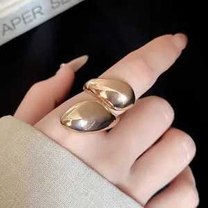 Close-up macro detail of an irregular water drop metal ring featuring a polished gold finish