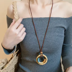 Detail of handmade wooden ring pendant necklace worn on a grey ribbed top.