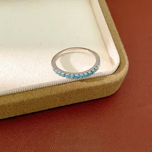 Minimalist silver eternity ring featuring light blue zircon stones inside a jewelry box