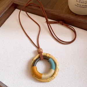 Detailed close-up of a bohemian bamboo ring pendant featuring vibrant colorful thread wrapping