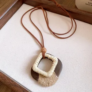 Close-up of a Maillard-style rhombic wooden pendant necklace with twine wrap detail.