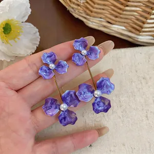 Detailed view of elegant purple enamel flower drop earrings with pearl center