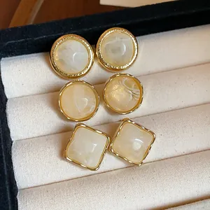 Close-up of retro resin geometric earrings with cream marble texture in gold frame