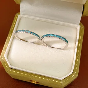 Detailed view of two minimalist silver-toned eternity rings with small blue zircon stones.