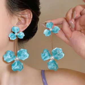 Detail shot of oversized turquoise enamel flower drop earrings with pearls