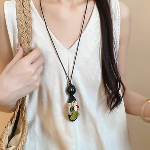 Detail view of vintage wooden pendant necklace with hemp rope, buttons and green tassel
