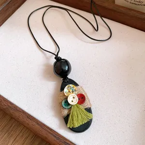 Detail view of ethnic bohemian necklace with black wood pendant and green tassel