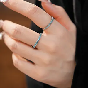 Detailed macro view of two minimalist slim silver rings with blue zircon pavé on a finger.
