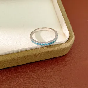 Close-up of a minimalist silver band ring featuring a row of tiny blue zircon stones.