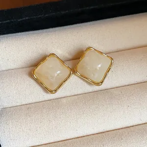 Macro view of vintage square resin stud earrings with gold frame in jewelry box