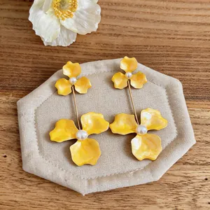 Detailed macro view of exaggerated yellow enamel flower drop earrings with white pearls