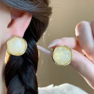 Macro detail of retro resin geometric stud earrings with elegant gold metal rim