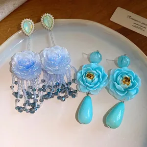 Dettaglio degli orecchini pendenti a fiore in resina blu su piatto di ceramica