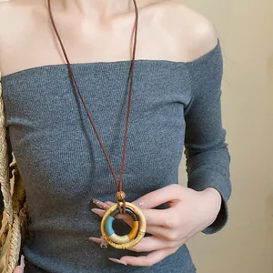 Close-up of a bohemian wooden ring pendant necklace with colorful thread wrapping