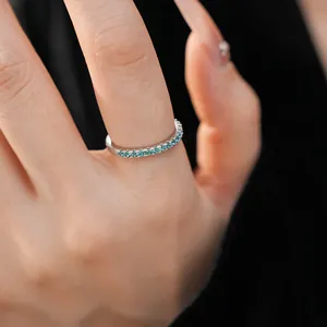 Detailed view of a minimalist silver eternity ring with shimmering teal blue cubic zirconia