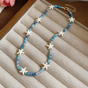 Gedetailleerde weergave van een blauwe kralenketting met witte zeesterren in een doos.