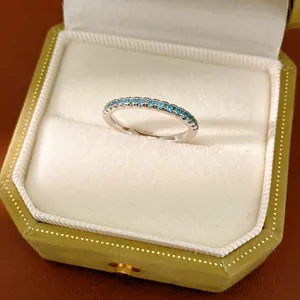 Close-up view of a minimalist silver ring with blue zircons in an elegant olive gift box.