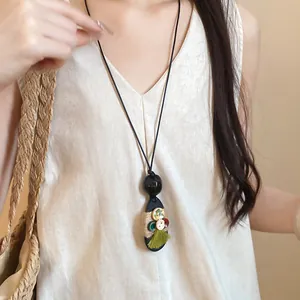 Elegant bohemian wood pendant necklace with hemp rope and green tassel on a model