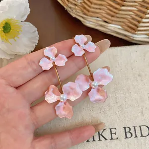 Close-up view of pink enamel flower drop earrings featuring elegant pearl center details
