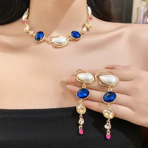 Primo piano di un set di collana e orecchini rétro con perle e cristalli blu su modella.