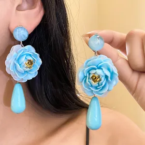 Orecchini a fiore in resina blu con pendenti a goccia, vista dettagliata in primo piano