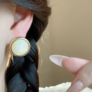 Close-up detail of vintage resin geometric stud earrings worn on model ear with braided hair