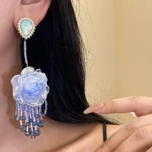 Dettaglio di orecchino a fiore in resina con perno a goccia e frange di perline.