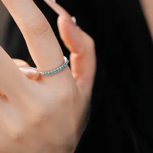 Close-up of minimalist silver band ring with a row of sparkling blue zircons