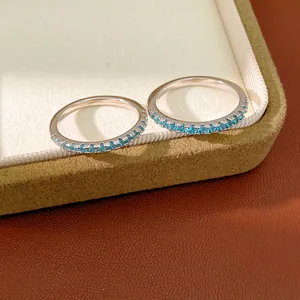 Close-up detail of elegant thin silver rings featuring sparkling blue zircon pavé setting