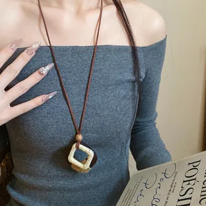 Close-up of Maillard style diamond pendant necklace with hemp rope and wood details.