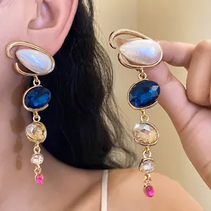 Dettaglio di alta qualità di orecchini vintage in oro con cristalli blu e perle bianche.