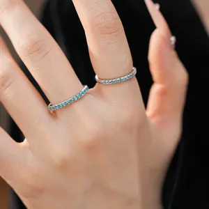 Detail view of minimalist thin silver eternity rings with blue zircon stones on fingers
